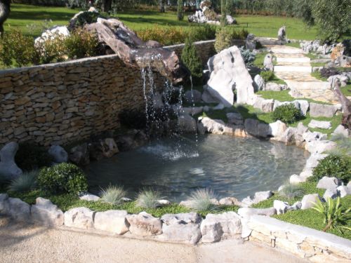 giardino roccioso con laghetto e cascata da vecchio tronco di ulivo